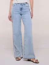 Pantalón jean de tiro alto y corte wide leg en color celeste, con detalle de puntilla en los laterales. Cuenta con cinco bolsillos, presillas para cinto y cierre frontal con botón.