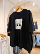 Remerón oversize negro de manga corta, confeccionado en algodón, con cuello redondo y estampa frontal de gato en un parche de tela blanca en contraste.