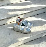 Sandalias de plataforma doradas, con suela ancha y tiras anchas cruzadas en el empeine y una tira ajustable en el tobillo.