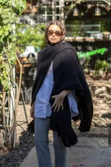 Ruana tejida a mano en punto arroz con lana merino, presenta un diseño envolvente con flecos en los extremos.