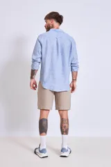 Camisa de corte regular con diseño de rayas verticales finas en tonos claros, cuello clásico y mangas largas con puños abotonados.
