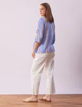 Blusa de algodón con diseño de rayas verticales en tonos azul, rosado y amarillo, escote en V con botones de madera, y mangas cortas con detalles de botones en los laterales.