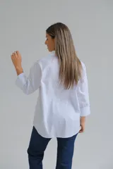 Camisa de corte clásico en color blanco, con cuello camisero, cierre frontal de botones y mangas largas con puños abotonados.