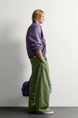 Cazadora regular fit de algodón color violeta con efecto lavado, cuello solapa y cierre de cremallera de doble dirección. Posee bordado frontal de gráficos Fruit of the Loom, bolsillos de vivo en la cadera y acabados con elástico.