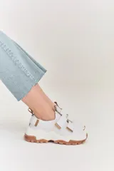 Championes de estilo urbano en color blanco con detalles en tono arena. Presentan un diseño con doble tira de velcro en el empeine, suela de plataforma dentada en color caramelo y tirador en el talón.