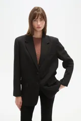 Blazer negro de poliéster, de corte holgado, con cuello solapa y cierre de un botón. Incluye dos bolsillos frontales con solapa y un bolsillo superior simulado.