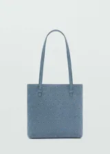 Bolso tipo tote de tamaño pequeño, confeccionado en piel bovina color azul con diseño troquelado de ojales metálicos en toda su superficie. Cuenta con doble asa de hombro y forro interior de poliéster.