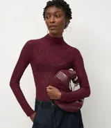 Blusa de encaje color bordó con cuello alto y mangas largas. Presenta un diseño ajustado al cuerpo con una leve transparencia y textura floral en el tejido.