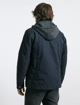 Campera técnica de tejido elástico en color azul marino, con capucha ajustable, cierre frontal y bolsillos laterales con cierre. Cuenta con forro interior de micro polar y ajuste en el ruedo.