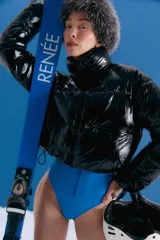 Campera puffer corta de color negro con acabado brillante, cuello alto y cierre frontal. Confeccionada en poliamida, presenta un diseño acolchado con bolsillos delanteros con cierre invisible.