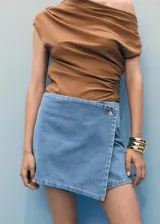 Short skort de tiro medio y diseño cruzado estilo falda pantalón, confeccionado en tejido de algodón denim vaquero con cierre de botón frontal.