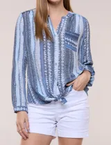Blusa de gasa Zac & Rachel con estampado de rayas verticales en tonos rosados, amarillos y blancos. Presenta escote en V con cuello mao, cierre frontal con botones, un bolsillo aplicado en el pecho, mangas largas con presilla para regular el largo y detalle de nudo en el dobladillo inferior.