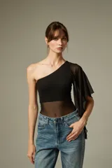 Top asimétrico de un solo hombro, color negro, con diseño ajustado al cuerpo y sección central y manga de tela transparente.