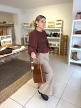 Blusa color chocolate con diseño de frunces elásticos en el frente y la espalda, mangas largas abullonadas con puños elásticos y corte peplum.