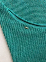 Buzo de tejido de punto con acabado brillante, confeccionado con hilado italiano. Presenta cuello redondo, mangas largas acampanadas y un corte holgado.