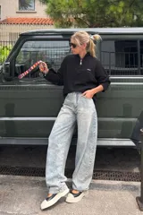 Sweater de tejido acanalado color negro, con cuello alto y cierre frontal parcial. Presenta mangas largas con puños ajustados y un parche con el logo de la marca en el pecho.