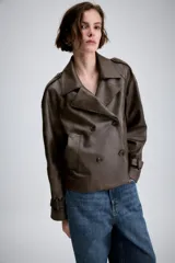 Cazadora de Zara Woman Collection confeccionada en material efecto piel color marrón oscuro. Presenta cuello con solapas, cierre frontal cruzado con botones, bolsillos delanteros y mangas largas con trabillas y hebillas ajustables en los puños.