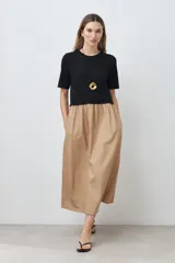 Vestido midi de corte recto, con top negro de mangas cortas y falda color beige.