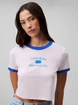 Remera cropped de manga corta color rosa pálido, con cuello redondo y ribetes azules. Estampado frontal con el logo de Calvin Klein y la inscripción 'New York City' en azul.