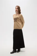 Sweater de tejido de punto color beige con estampado jacquard de leopardo en color negro. Presenta cuello redondo amplio y puños y ruedo acanalados.