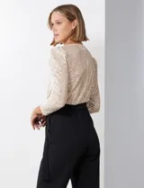 Enterito combinado de fiesta marca Julia Jordan. El torso es de lentejuelas color beige con escote en V cruzado y mangas largas abullonadas. La cintura es elastizada con lazo de ajuste y el pantalón es negro con bolsillos verticales. La espalda tiene cierre invisible y el torso está forrado.