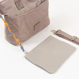 Cartera tipo tote de color camel con diseño acolchado de líneas curvas. Cuenta con doble asa de mano, correa larga ajustable y extraíble, y un bolsillo frontal con cierre que incluye un tirador decorativo con cordón multicolor.
