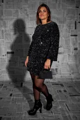 Vestido corto de fiesta color negro, recubierto íntegramente de lentejuelas. Presenta un diseño de mangas largas rectas y escote redondo.