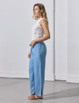 Pantalón celeste de lyocell, corte ancho, con pretina elastizada con lazo de ajuste, bolsillos verticales y ruedo desflecado.