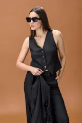 Chaleco sastrero negro de corte entallado, con escote en V y cierre frontal de botones. Presenta un diseño estructurado con bolsillos laterales decorativos.