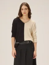 Buzo de tejido de punto bicolor con diseño dividido en negro y beige, cuello en V y mangas largas.