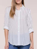 Camisa de calce holgado en género liviano con estampado a rayas verticales, cuello camisero clásico y abotonadura frontal a tono. Presenta mangas largas regulables con presilla y botón para ajustar a tres cuartos, espalda con canesú y suave pliegue central, y ruedo curvo estilo camisero.