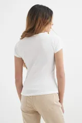 Remera básica color crema de algodón, con cuello redondo y mangas cortas.