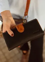 Billetera larga de cuero color beige con cierre de broche marrón y logo grabado.