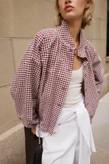 Chaqueta de manga larga con estampado de cuadros vichy en tonos marrón y blanco, cuello camisero, cierre frontal con botones y bajo ajustable con cordón.