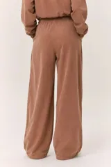 Conjunto deportivo de dos piezas compuesto por un buzo cropped de cuello alto con cordón ajustable y un pantalón estilo clochard de corte holgado con cintura elástica regulable y bolsillos laterales. Ambas prendas están confeccionadas en tejido técnico ligero con acabado suave al tacto.