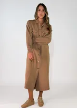 Vestido camisero midi de algodón, color beige, con cuello clásico, cierre frontal de botones y bolsillos con solapa en el pecho. Presenta mangas largas con puños abotonados y un corte recto.