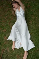 Vestido largo con pechera de cuero metalizado y falda tejida con hilo de lurex brillante. Presenta un diseño de cuello halter y corte fluido.