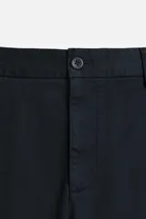 Pantalón chino de algodón color crema, corte regular fit, con cierre frontal de cremallera y botón, bolsillos delanteros y bolsillos traseros de vivo con botón.