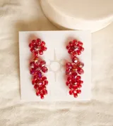 Par de aros colgantes con forma de racimo de cristales facetados color rojo.