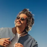 Lentes de sol Sunski Baia con montura redonda negra y detalles metálicos plateados. Lentes polarizados verdes que bloquean el 100% de los rayos UVA/UVB/UV400.