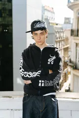 Hoodie negro con cierre, corte regular y lavado gastado. Estampado con logo en el pecho y diseños en las mangas.