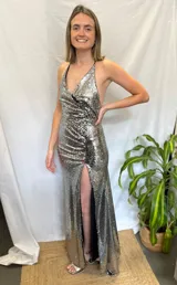 Vestido largo plateado de lentejuelas con escote en V, espalda baja y tajo en la pierna.
