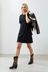 Vestido corto negro con cuello redondo, mangas cortas y detalle de flecos en el pecho.