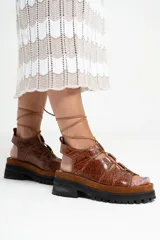 Sandalias de cuero color marrón con textura de cocodrilo, plataforma con suela track y tiras finas que se atan al tobillo.