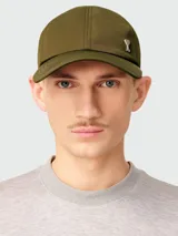 Gorra de béisbol color verde oliva, confeccionada en nylon, con visera curva y un pequeño pin metálico con el logo de corazón de Ami Paris en el frente.