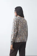 Sweater de punto con diseño de estampado animal print abstracto en tonos tierra y azul claro. Presenta cuello redondo a la base, mangas largas levemente amplias y terminaciones acanaladas en puños y ruedo.