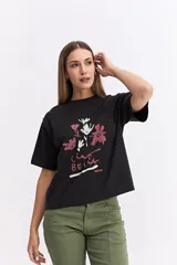 Remera de corte oversize color negro, con silueta amplia y caída relajada. Presenta una estampa frontal con motivos florales y la frase 'Ciao Bella' en tonos rosados y blancos.