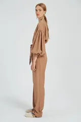 Mono largo color beige con cierre frontal, mangas abullonadas y cinturón con lazo.