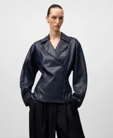Chaqueta estilo biker de efecto cuero color azul marino, con solapa ancha, cierre cruzado frontal y cintura entallada. Presenta mangas largas y bolsillos delanteros con cremallera invisible.
