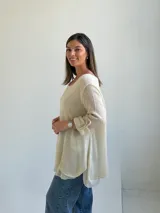 Sweater de punto color beige, de corte amplio y holgado, con escote redondo y mangas largas con presillas para arremangar.